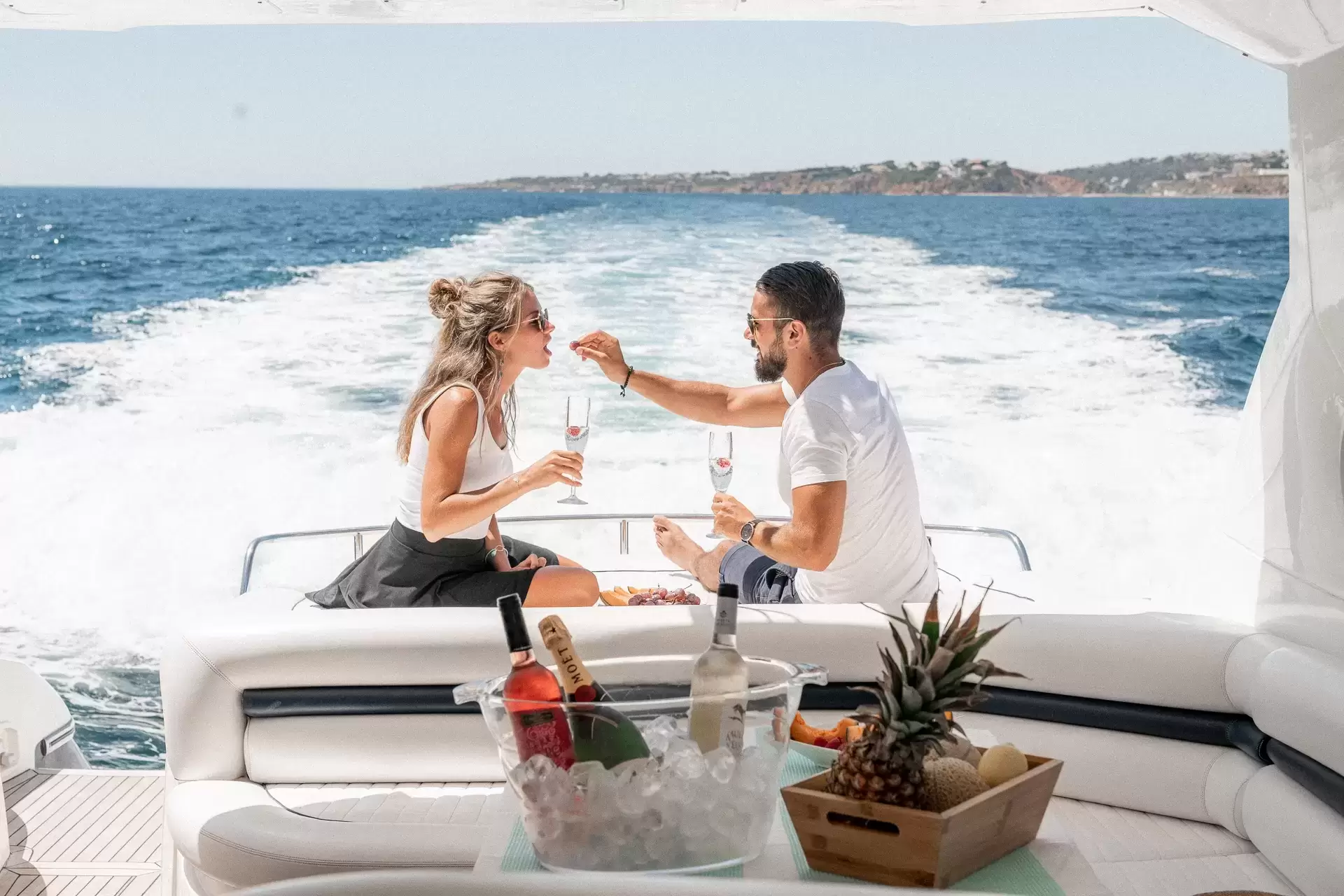 the guy feeds the girl on the yacht with strawberries from his hand